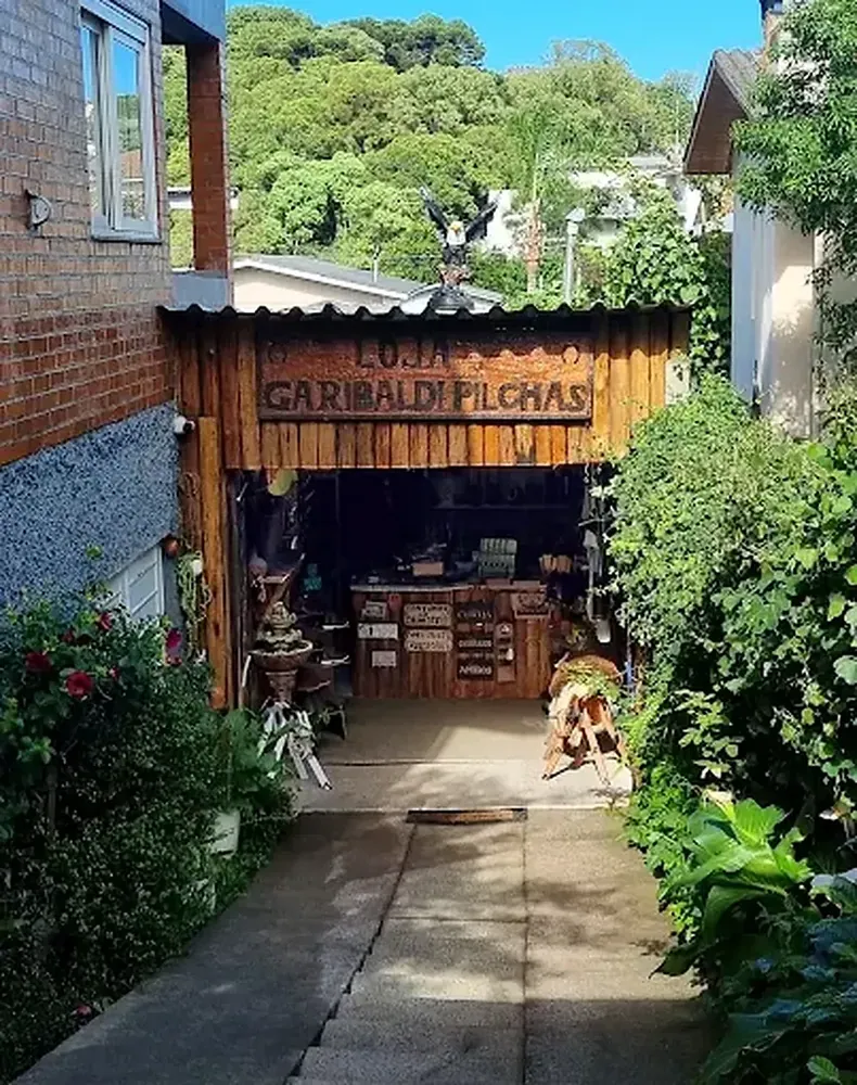 Fachada da Garibaldi Pilchas, com a placa de madeira sobre o corredor de entrada